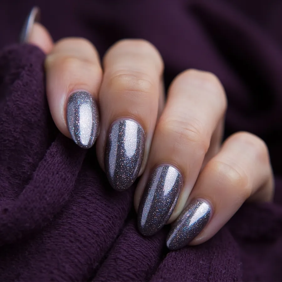 Silver cat eye gel nails on almond shaped nails with a soft band of light across each nail, resting on a deep purple knit.